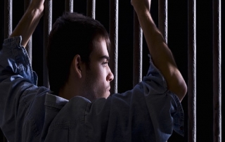 Imprisoned man, looking down, seized to a few bars
