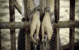 hands tied with rusty chain behind the bars